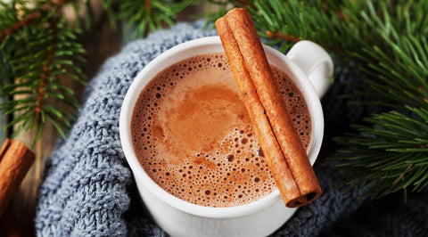 Hot chocolate with a cinnamon stick in a white mug - Chocolate & More Delights